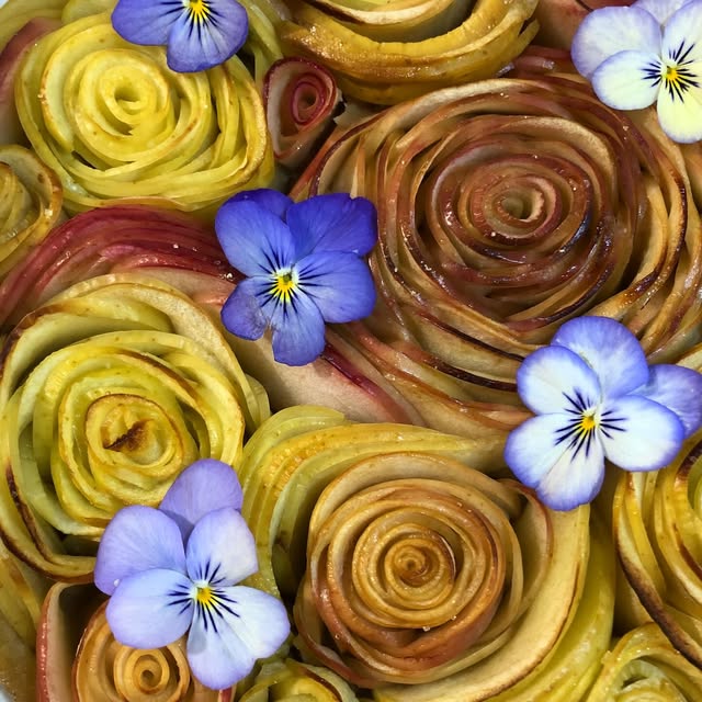 Tarte aux fruits en forme de roses et aux fleurs violettes
